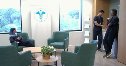 Healthcare staff relaxing and chatting in modern staff lounge, nurse using smartphone