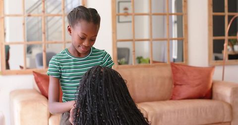 African mother and daughter sharing warm conversation on living room sofa, family moment