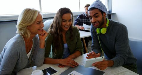 Diverse Group Engaging in Discussion with Tablet in Modern Workspace
