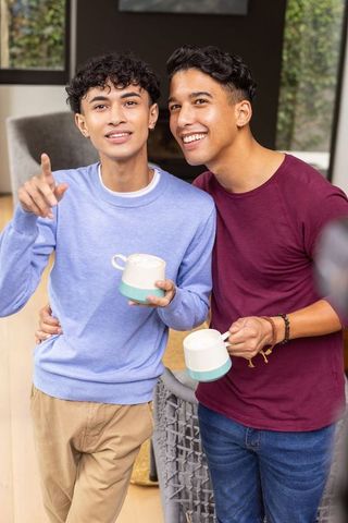 Candid friendship indoors with coffee mugs