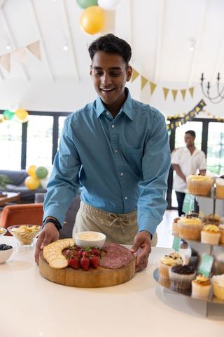 Friends arranging appetizers on countertop during celebration