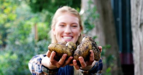 Smiling Gardener Holding Freshly Harvested Potatoes Outdoors