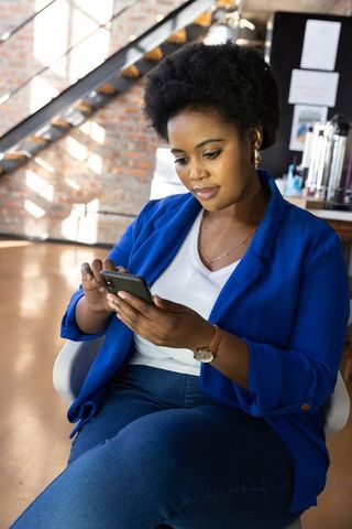 African american woman using smartphone in modern workspace