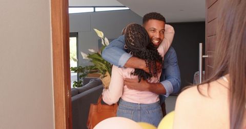 Diverse Friends Celebrating with Hugs and Gifts at Party Entrance