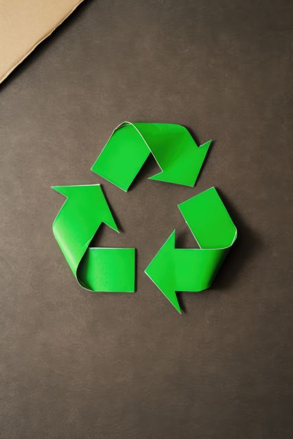 Green arrows recycling sign and paper on black background, created using generative ai technology. Recycling, environment and climate change awareness concept digitally generated image.