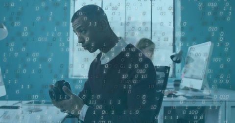 Inspecting dslr camera while analyzing binary data overlay in creative office workspace