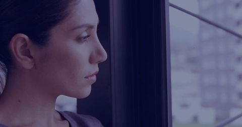 Pensive Young Woman Gazing Out Window in Urban Setting