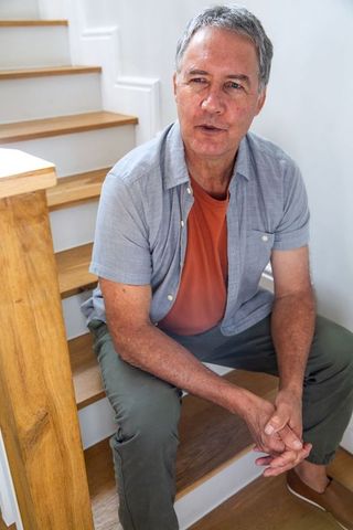 Senior man sitting on staircase in cozy minimalist home interior
