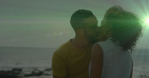 Romantic Couple Kissing by Ocean Sunset with Scenic Lens Flare