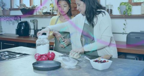 Mother and daughter kneading dough at kitchen island, teaching baking and teamwork