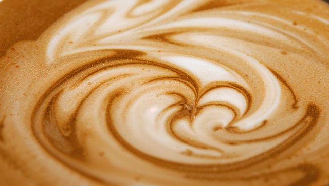 Close-up of intricate swirling latte art design with warm tones