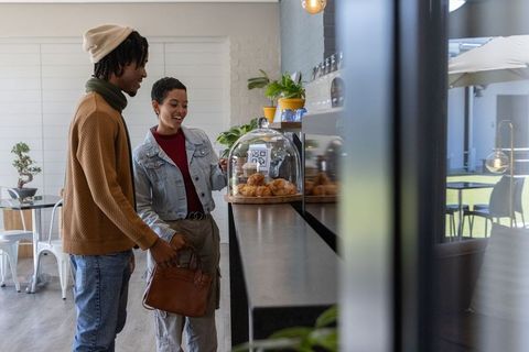 African American Couple Choosing Pastries and Scanning QR Code at Modern Cafe Counter