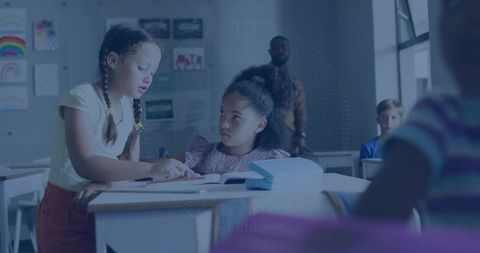 Schoolgirl Pointing While Guiding Classmate Over Lesson in Classroom