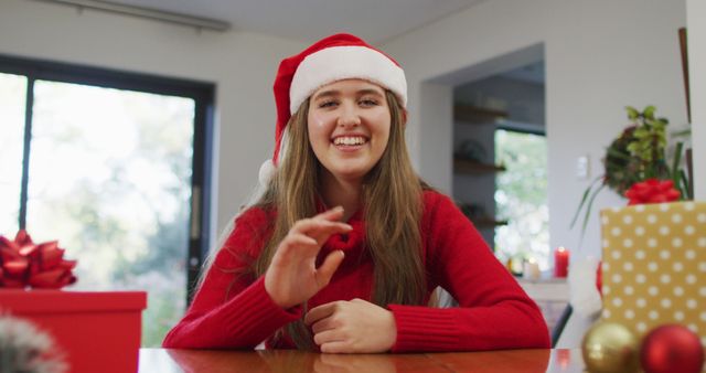 Smiling caucasian woman wearing santa hat making image call at homeh waving. christmas, communication technology and celebration.