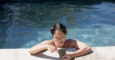 Young Asian Man Checking Smartphone Relaxing in Swimming Pool - Download Free Stock Images Pikwizard.com