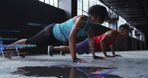 Performing synchronized plank push-ups in industrial gym for strength training