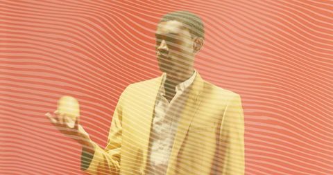 Man in yellow blazer posing with abstract sphere on red striped background