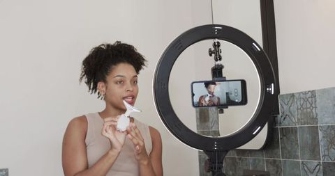 Beauty vlogger recording vertical makeup tutorial with ring light, mirror and applicator