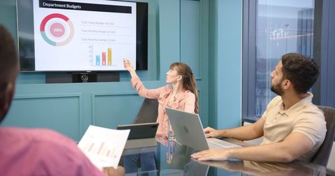 Woman presenting budget figures to focused colleagues in modern office