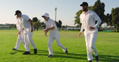 Cricket players jogging across sunlit outfield during team training and warmup