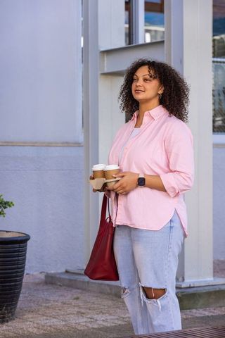 African american woman holding three takeaway coffee cups on sidewalk in pastel shirt