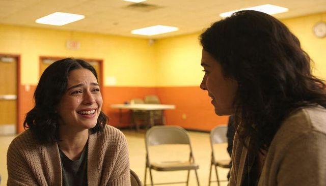 Tearful woman receiving comfort from friend during community support group meeting