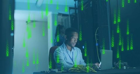 IT Specialist Analyzing Data on Laptop Amid Server Racks