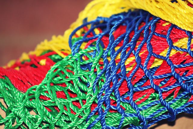 Bright, intertwined plastic ropes form an intricate net structure in vibrant colors. Ideal for backgrounds, textile industry, art, and design projects, highlighting texture and pattern details.