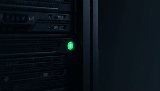 Rack-mounted server bay with green led indicating active drive in dark datacenter