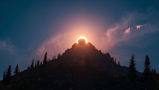 Jagged mountain summit glowing with halo during annular solar eclipse at twilight