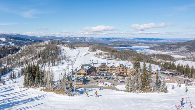 Aerial alpine ski resort with chalet lodges, chairlifts, skiers, snowy mountain landscape