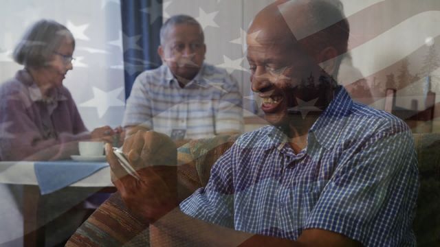 A senior man is using a mobile phone with his friends sitting in the background at a retirement home. Global business data processing and technology concept digitally generated video.