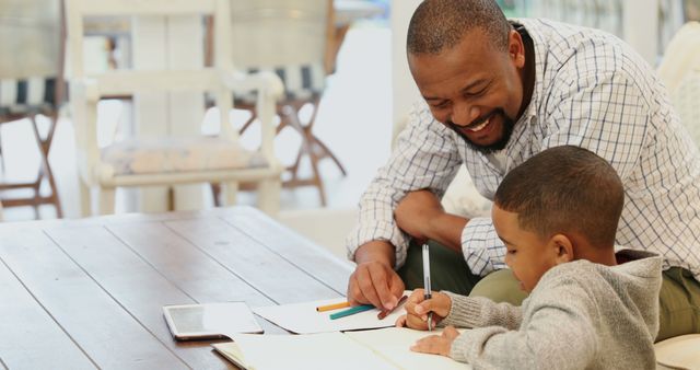 Smiling Father Helping Son with Schoolwork at Home - Download Free Stock Images Pikwizard.com