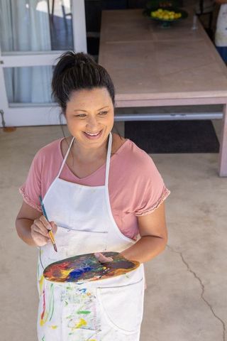 Smiling Female Artist with Paint Palette in Rustic Setting
