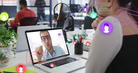 Remote team collaborating via video call on laptop in modern open office with chat icons