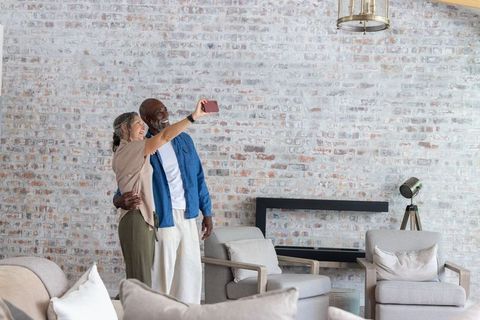 Senior couple posing for selfie in cozy modern rustic living room with exposed brick wall