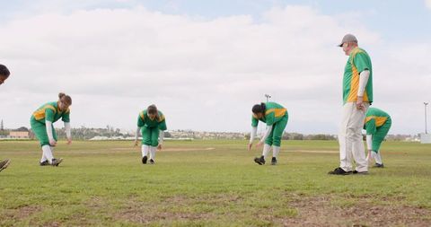 Baseball Team Warm-up on Field with Coach Observing