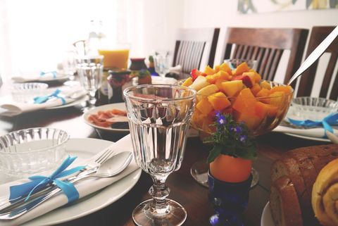 Spring brunch tabletop with fresh fruit salad, crystal glasses, bread and blue ribbon