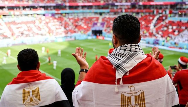Passionate egyptian fans wearing flag and keffiyeh cheering during football match