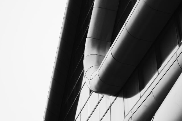 Shows close-up view of a modern architectural structure with curved lines and geometric patterns in black and white format. Suitable for use in articles on contemporary architecture, abstract art, urban landscapes, and minimalist design. Highlighting the aesthetic appeal of modern building elements.