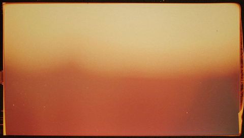Analog film frame with light leak and warm gradient, vintage grain and border artifacts