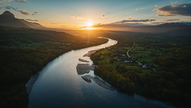 Sunset river meander over rural valley with sandbars, village road and mountain ridges