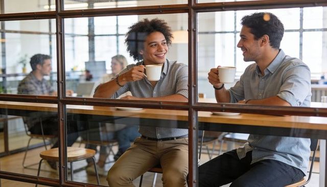 Smiling colleagues sharing coffee and chatting at modern cafe-style office counter
