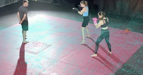 Female Boxers Sparring Under Spotlight While Coach Observing on Padded Gym Mats, Training