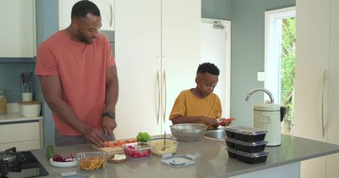 African american father and son preparing healthy meals at kitchen island