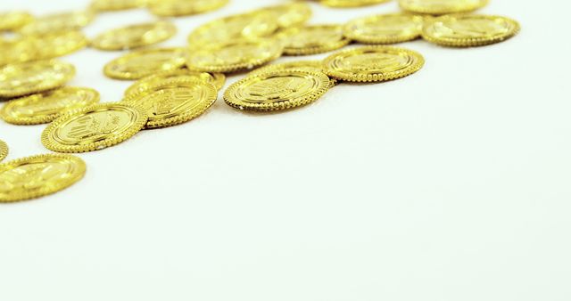 Scattered golden coins lie on a white surface, creating a sense of abundance and wealth, with copy space. Their shiny appearance suggests prosperity and could symbolize financial success or savings.