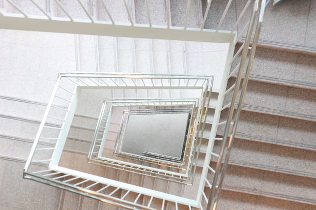 Modern spiral staircase with symmetrical geometric pattern viewed from above. Useful for architectural blogs, interior design websites, educational materials on geometry, backgrounds for presentations emphasizing symmetry, or projects involving modern building designs.
