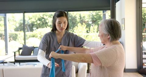 Caregiver Assisting Senior Woman with Physical Therapy at Home