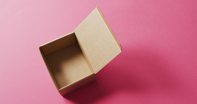 Image of open, empty cardboard box and copy space on pink background. christmas, tradition and celebration concept.
