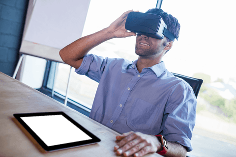 Man Interacting with Virtual Reality Headset Near Tablet